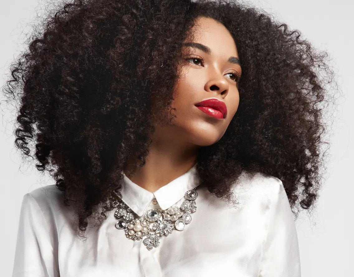 Ogle School student model with voluminous curls and a statement necklace